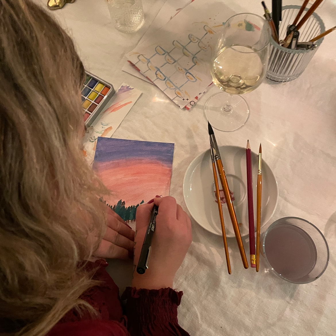 en jente som maler en solnedgang med akvarellmaling